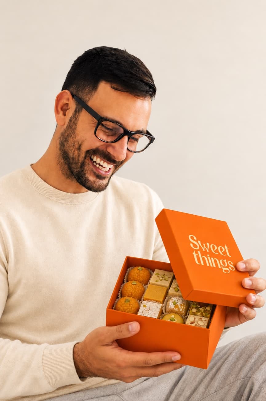 A man opening a box of assorted Sweet Things mithai